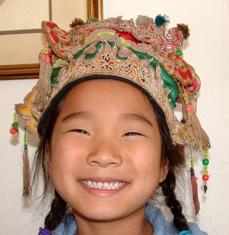 Smiling young Chinese girl wearing a traditional hat